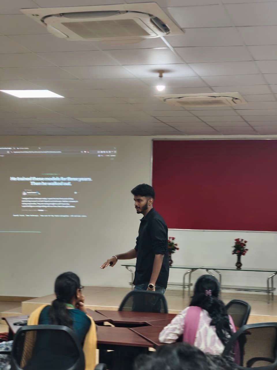 Kanish pointing at a slide while students watch