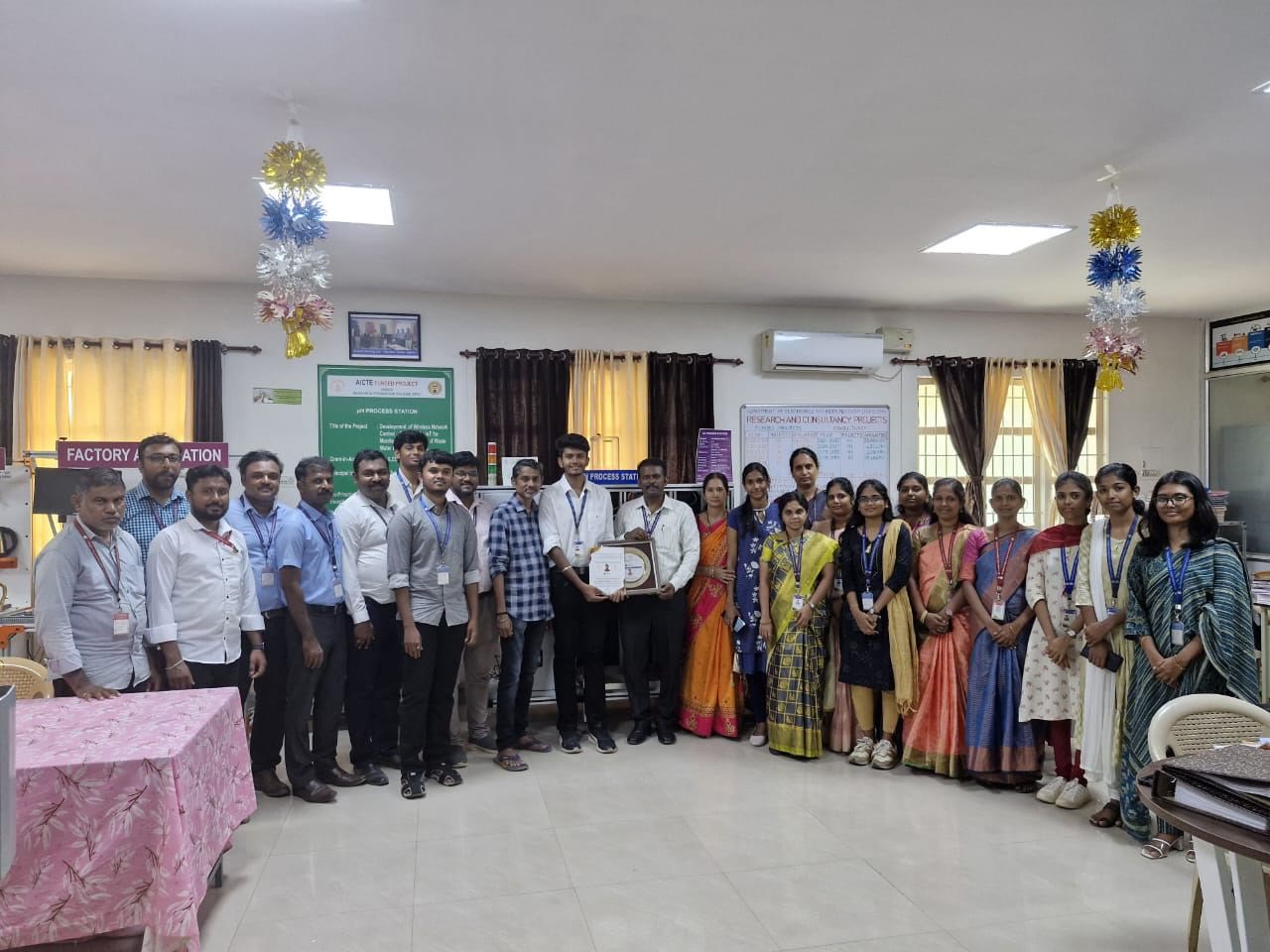 Kanish holding the ABARAM plaque with the entire Electronics and Instrumentation faculty in the department lab
